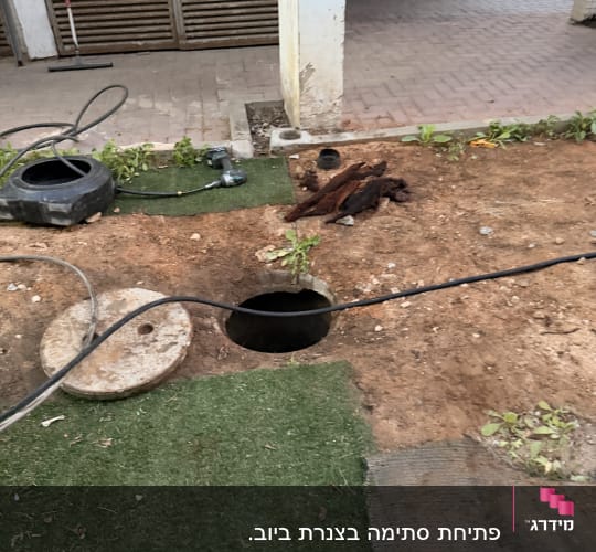 עבודת תחזוקה עם צינור וכלים ליד פתח ביוב